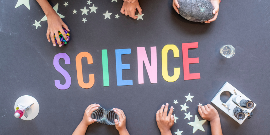 The word 'Science' is spelt out on a table in colourful letters.
