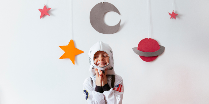 Kid in a space suit with planets above their head.