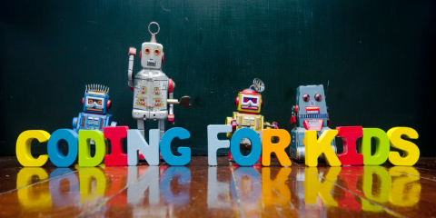 Blocks forming "Coding for Kids" with robots standing beside it.