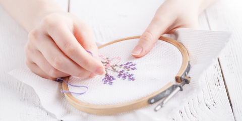 A person cross stitching a flower.