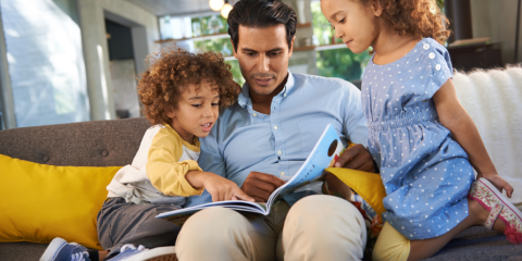 Family sitting together on a couch, reading a book.