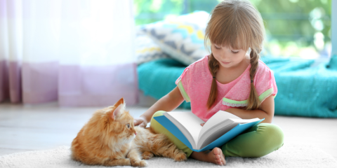 A child reading to a cat.