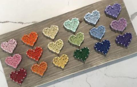 wooden board with string art hearts in rainbow colours