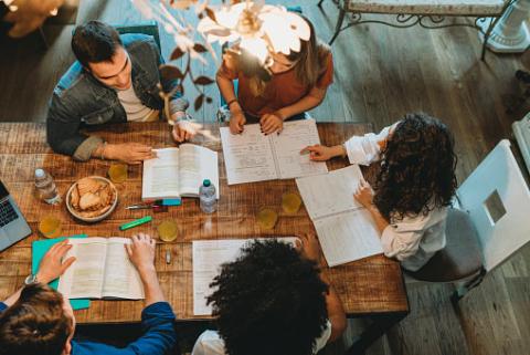 People gathered around a table with books and papers.