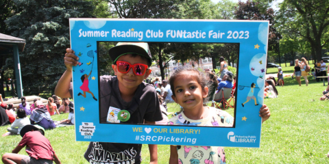 Children holding a sign celebrating Summer Reading Club.