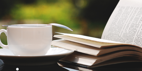 Teacup beside an open book.