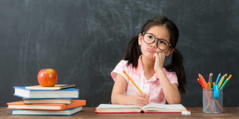 A kid pondering what to write in a book.