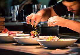 A person is garnishing a plate of food