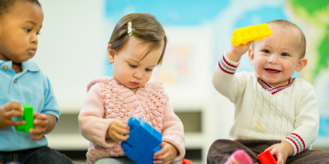 Children smiling and playing with blocks 