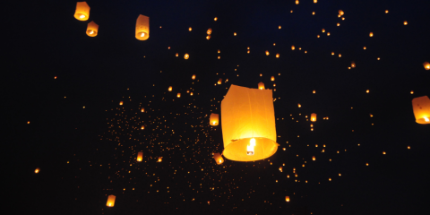 Paper lanterns floating in the night sky.