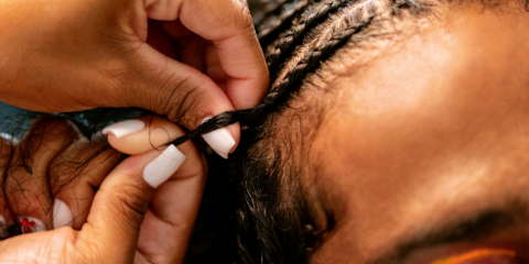 Black woman's hair being braided. 