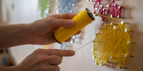 Hands creating string art. 