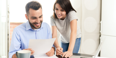 Woman looking over man's shoulder while he regards a document.