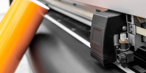 Roll of vinyl leaning against a vinyl cutter. 