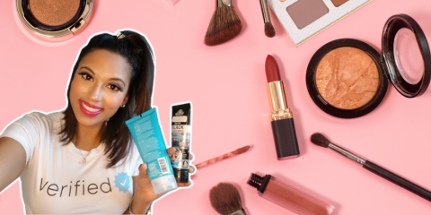 Tiera Dee holding beauty products, in front of a background with more beauty products. 