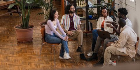 Group of people sitting in a circle, speaking.