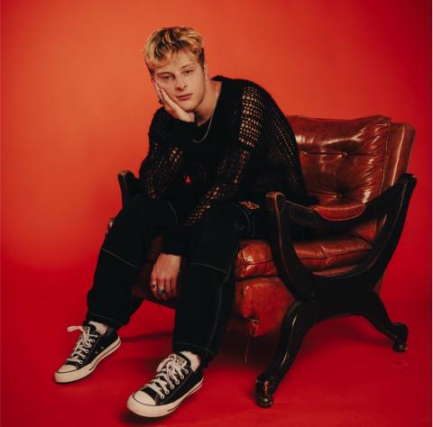 Joseph Robinson sitting in a chair infront of a red background