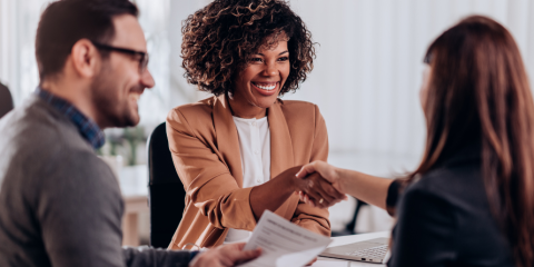 Woman speaking with man and woman at table.