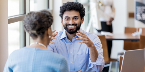 Two people speaking at a table. 