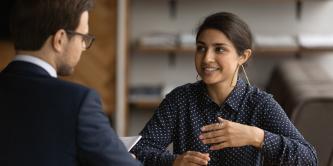Two people speaking at a table. 