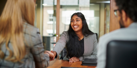 Woman speaking with man and woman at table.