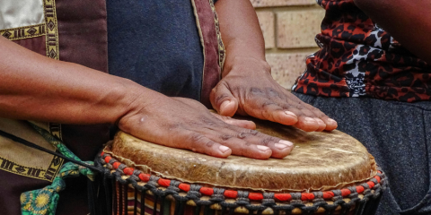Hands atop a drum's surface. 