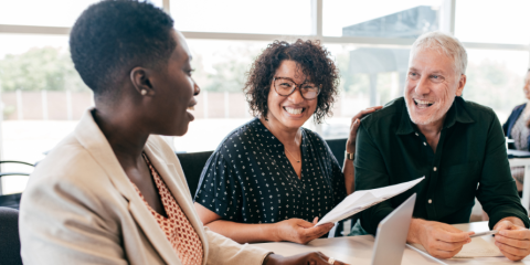Smiling woman holding a sheet of paper, a man and woman on either side of her. 
