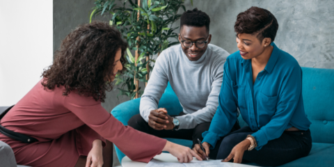 Woman showing a couple something on a tabletop. 
