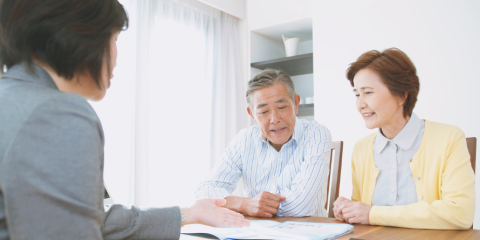 Woman speaking with two seniors at a table. 
