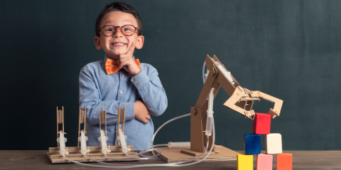 kid with a robot arm he made out of cardboard.
