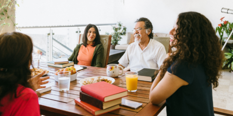People seated around a table filled with books. 
