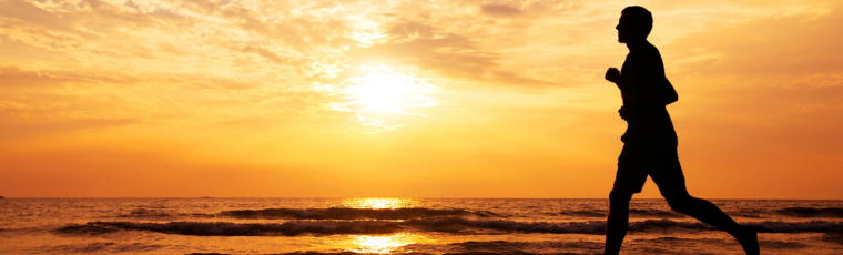 silhouette of person running on the beach at sunrise