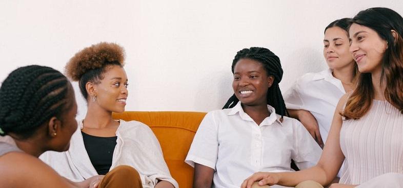 a group of women smiling and talking while sitting on a couch together