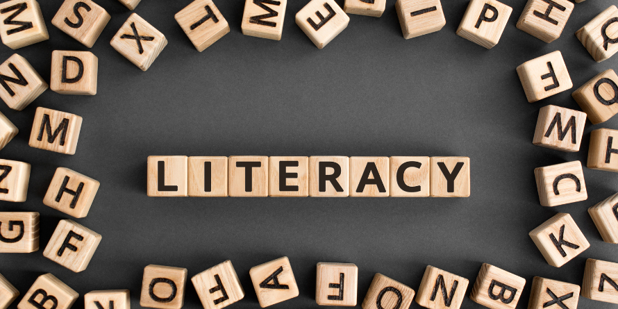 The word 'Literacy' is put together with blocks on a table.