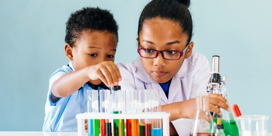 Two kids putting colourful liquid in test tubes.