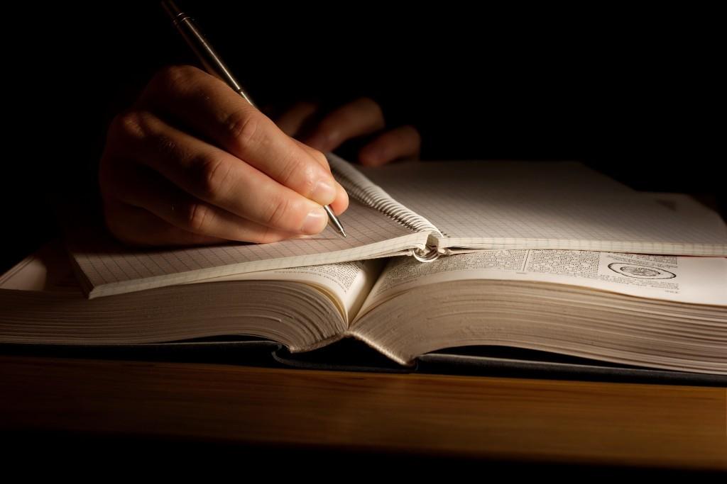 Person writing in book.