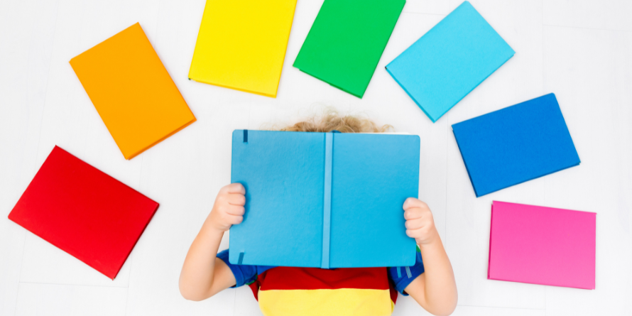 A kid lying on the floor with books around them.