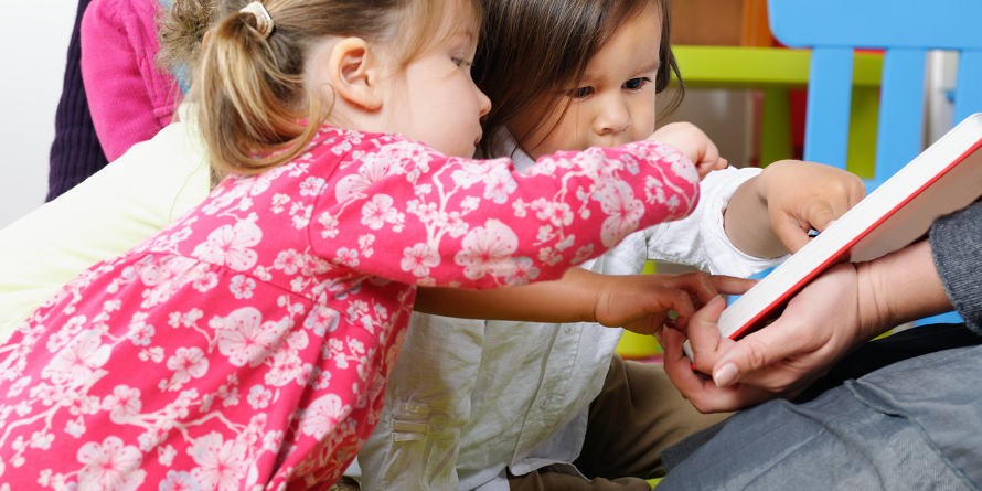 Two toddlers reading a story 