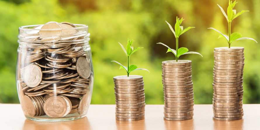 Coins in a jar and stacked in various towers beside the jar.