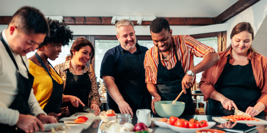 Group of smiling adults around a table with ingredients.