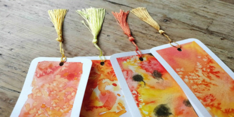 Four paper bookmarks with splatters of red, orange and yellow paint