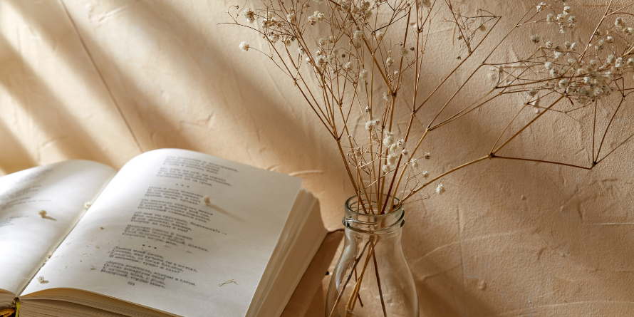 Open book of poetry beside a potted plant, sunlight shining. 