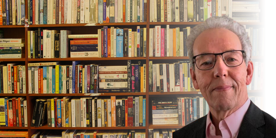 James L. Turk in front of a shelf of books. 