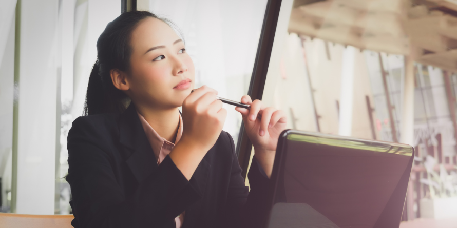 Woman thinking at a laptop.