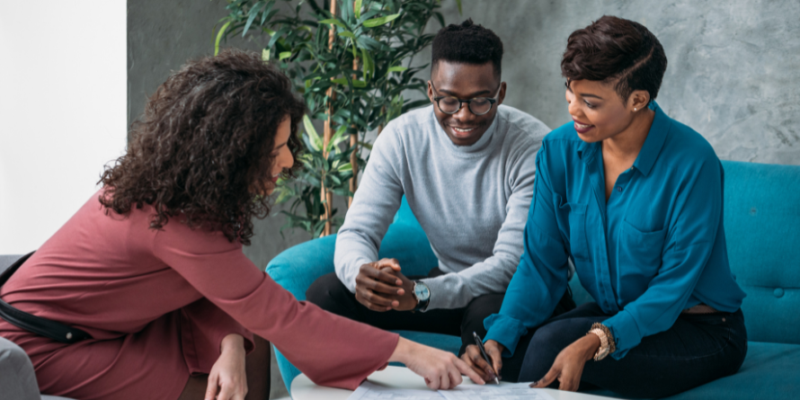 Woman showing a couple something on a tabletop. 