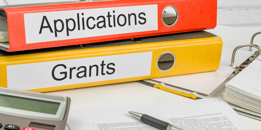 Two binders stacked atop each other, the top says 'applications', the bottom says 'grants'. 
